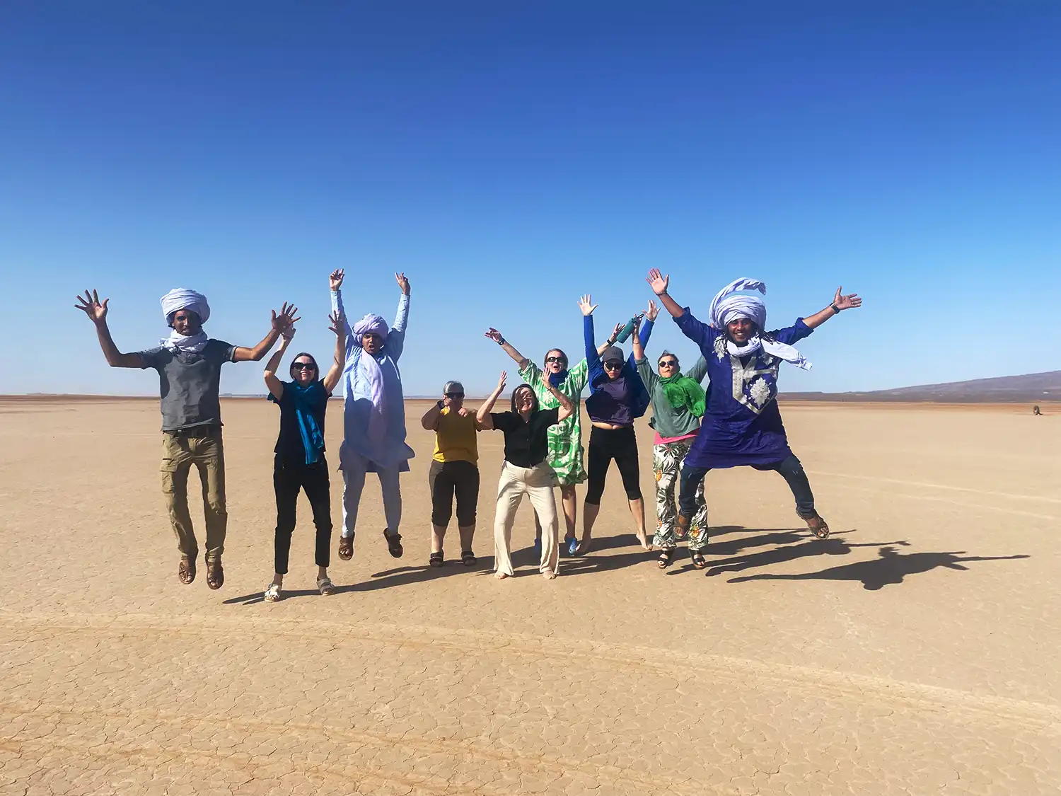 Tourists jumping on the dry Lake Iriki near Foum Zguid