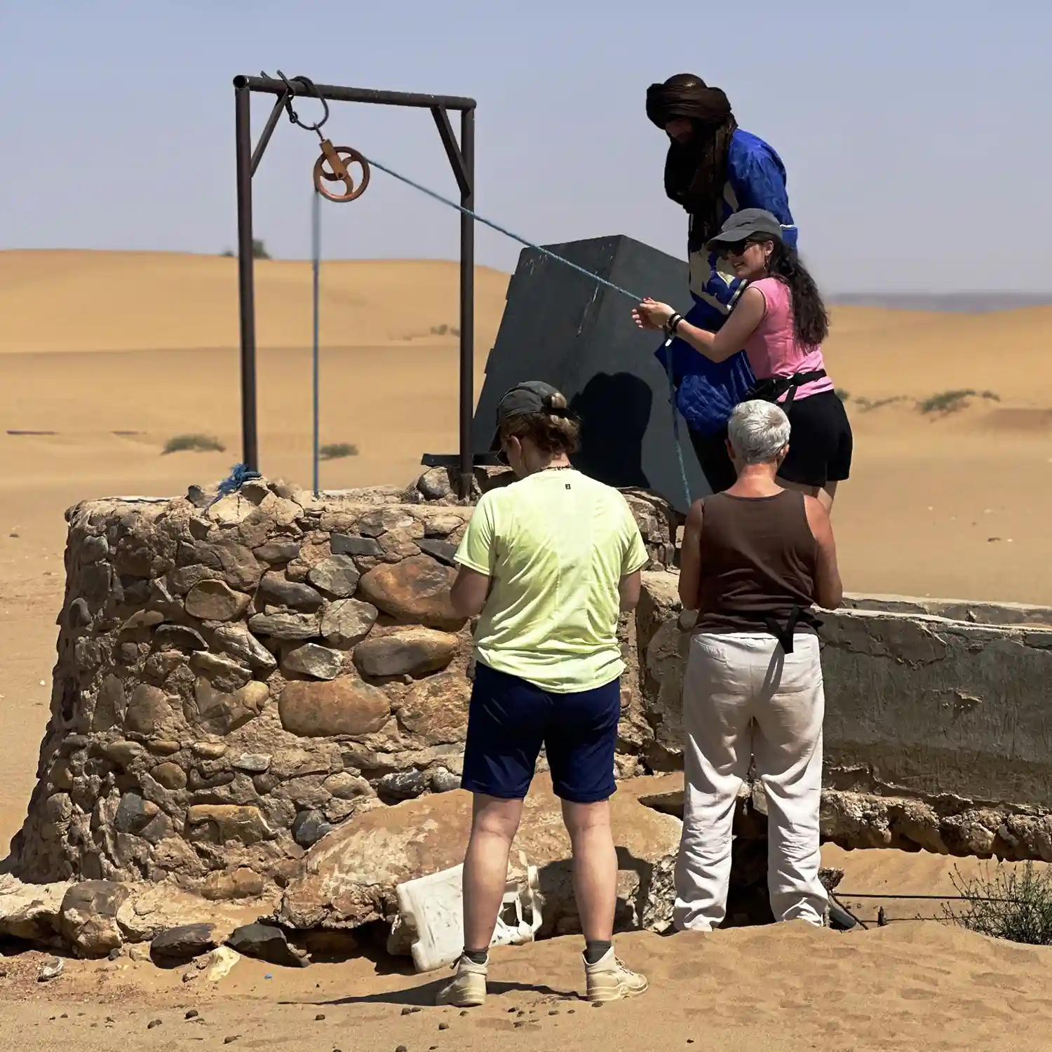 Travelers visiting a traditional water well in the Sahara desert near Erg Chigaga